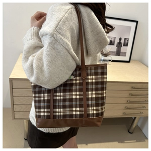 Detail of checkered tote bag showing leather handles and canvas texture in lifestyle setting