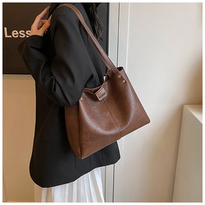 Detail of dark brown leather tote bag with fashion logo and golden rivet accents