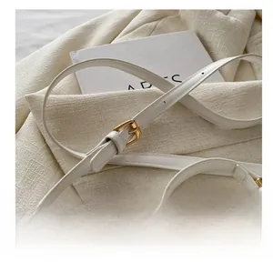 Detail of adjustable shoulder strap with gold buckle on white leather crossbody bag