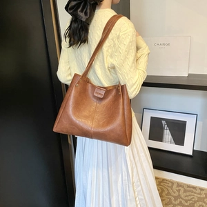 Brown leather tote bag with vertical stitching and metal rivets for minimalist fashion