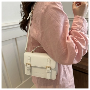 Detail of white leather crossbody bag featuring gold buckles and embossed logo