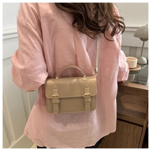 Detail of khaki crossbody bag with vintage vertical straps and gold hardware on model