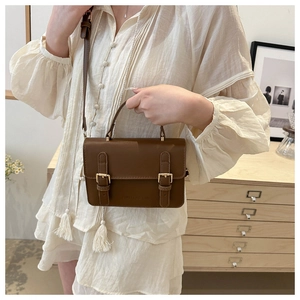 Close-up of vintage brown leather handbag featuring buckle straps and embossed logo detail