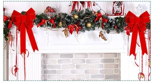 Detailed view of red velvet Christmas bows and green pine garland with gold ornaments