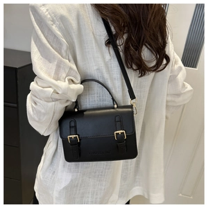 Close-up of black crossbody bag featuring matte leather texture and gold hardware detail