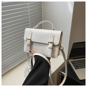 Detail of white minimalist crossbody square bag featuring dual metal buckle straps