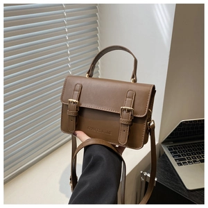 Detailed view of brown retro small square bag with golden buckles and shoulder strap