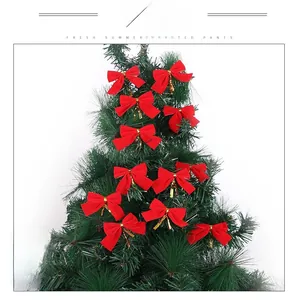 Dettaglio di 12 fiocchi natalizi in velluto rosso con nastri dorati su un albero verde
