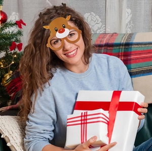 Close-up of reindeer Christmas glasses worn by a girl near a festive Christmas tree