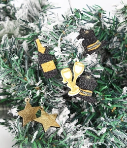 Détail de boucles d'oreilles festives noir et or sur des branches de pin enneigées