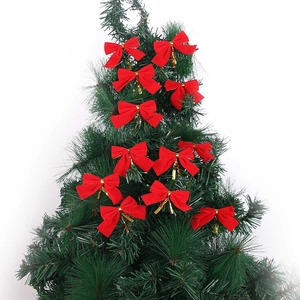 Red velvet Christmas bows with gold ties hanging on green pine tree branches decoration