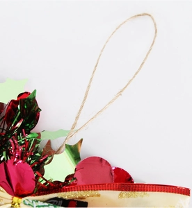Detail of Christmas wreath featuring red and green metallic leaves and natural twine loop