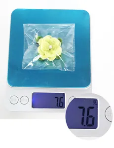 Detail showing plush flower hair clip weight 7.6g on a blue electronic digital scale