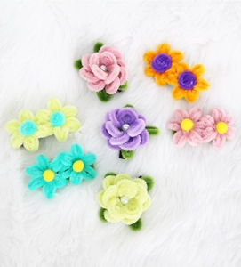 Macro detail of colorful plush flower hair clips with pearls on a soft white fur background