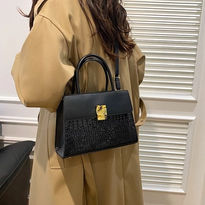 Vintage black crocodile-pattern handbag with gold buckle shown on a model