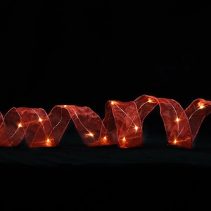 Detail von rotem Weihnachtsschleifenband mit warmen LED-Lichtern auf Schwarz