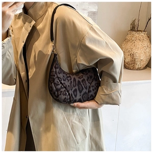 Close-up of leopard print crescent bag with golden metal hooks and black strap texture