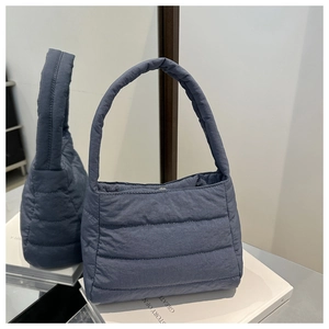 Detailed view of grey-blue quilted padded handbag with soft horizontal stitching and wide strap