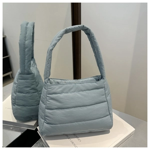 Detail of light blue quilted puffer handbag showing padded texture and mirror reflection
