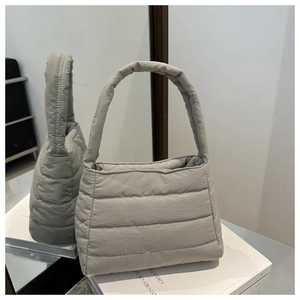 Close-up of light gray quilted puffer shoulder bag with soft padding and horizontal stitching