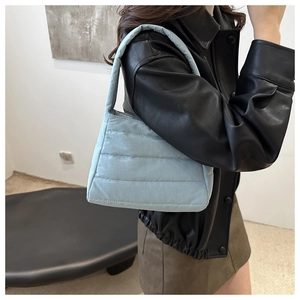 Detail of light blue quilted puffer shoulder bag showing soft padded texture and stitching