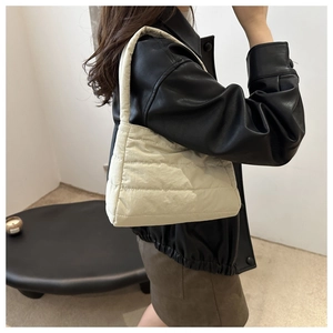 Close-up of cream quilted puffer shoulder bag with stylish cross-stitch padding