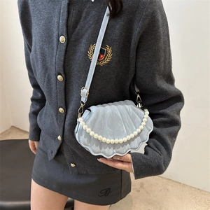Chic light blue shell crossbody bag with pearl handle and textured pattern on shoulder