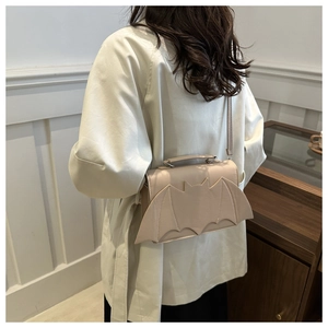 Chic cream bat wing crossbody bag shown on a model in a minimalist French style setting