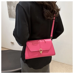 Detail of fuchsia leather crossbody bag with elegant gold circular buckle on black shirt