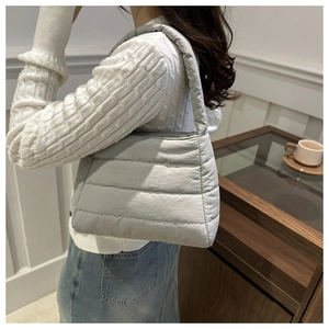 Close-up of a light grey quilted shoulder bag with soft padded nylon texture