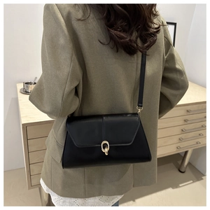 Chic black leather shoulder bag with gold clasp shown on olive green suit for autumn style