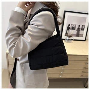 Detailed side view of black puffer shoulder bag with horizontal quilted stitching detail