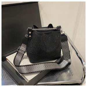 Détail du sac seau noir en strass avec large bandoulière tissée en V et boucles argentées