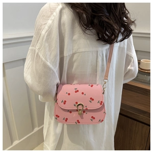 Modèle portant un sac besace rose avec imprimé cerises et boucle en métal doré