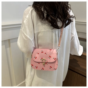 Détail du sac bandoulière rose en cuir PU avec motif cerise et fermoir doré chic