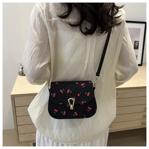 Détail du sac besace noir avec imprimés cerises et boucle fer à cheval dorée