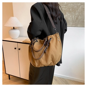 Detail view of large brown canvas tote bag with leather straps and silver metal eyelets