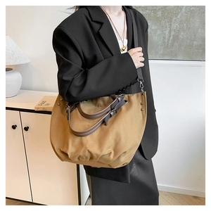 Detail shot of khaki canvas tote with brown leather handles and adjustable shoulder strap