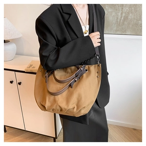 Detail of dark khaki canvas tote bag with leather straps in a cozy home setting
