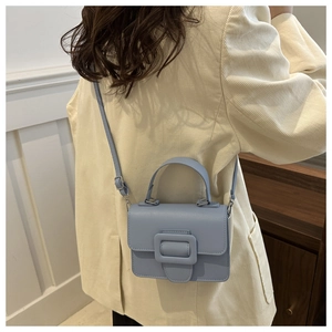 Woman wearing a light blue square crossbody bag with large buckle on corduroy jacket