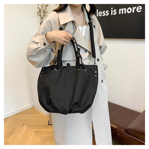 Detail of black canvas tote bag with metal rivets and adjustable shoulder strap
