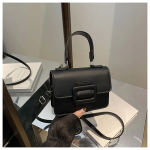 Détail d'un sac à main en cuir noir mat avec boucle carrée élégante et poignée courte