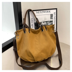 Detail of the vintage canvas tote bag with leather handles and metallic rivet accents