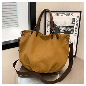 Detailed view of ginger yellow canvas bag with brown handles and sturdy metal rivets