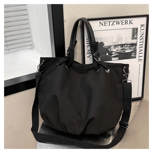 Detail of black canvas tote with cloud silhouette, leather handles, and adjustable strap