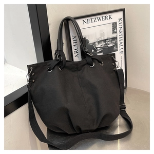 Detail of black canvas tote bag with adjustable shoulder strap and silver hardware accents