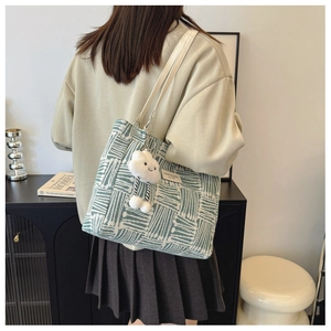Detail of green and white striped knit tote bag with cloud pendant in minimalist interior