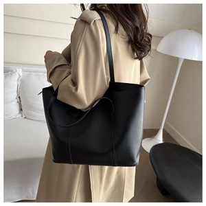 Minimalist black matte leather tote bag shown in a cozy interior setting for commuting