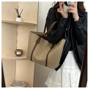 Detail of a large beige tote bag with brown straps, shown in a stylish urban outfit