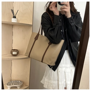 Detail of a large beige and brown tote bag shown in a mirror selfie for daily commute use
